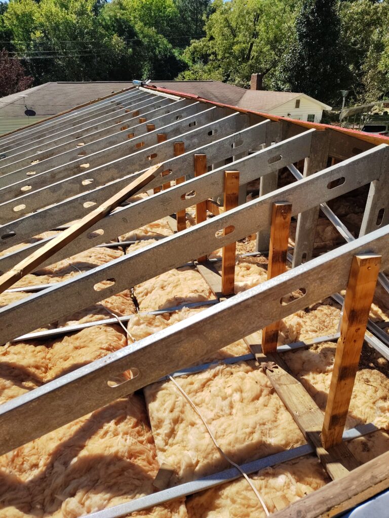 Roof structure exposed with decking removed, showing fascia and roof edge areas vulnerable to water damage from improper gutter installation.