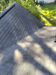 Finished slope: the repaired shingle courses blended into the existing roof and the debris cleared off so water runs clean to the gutters again