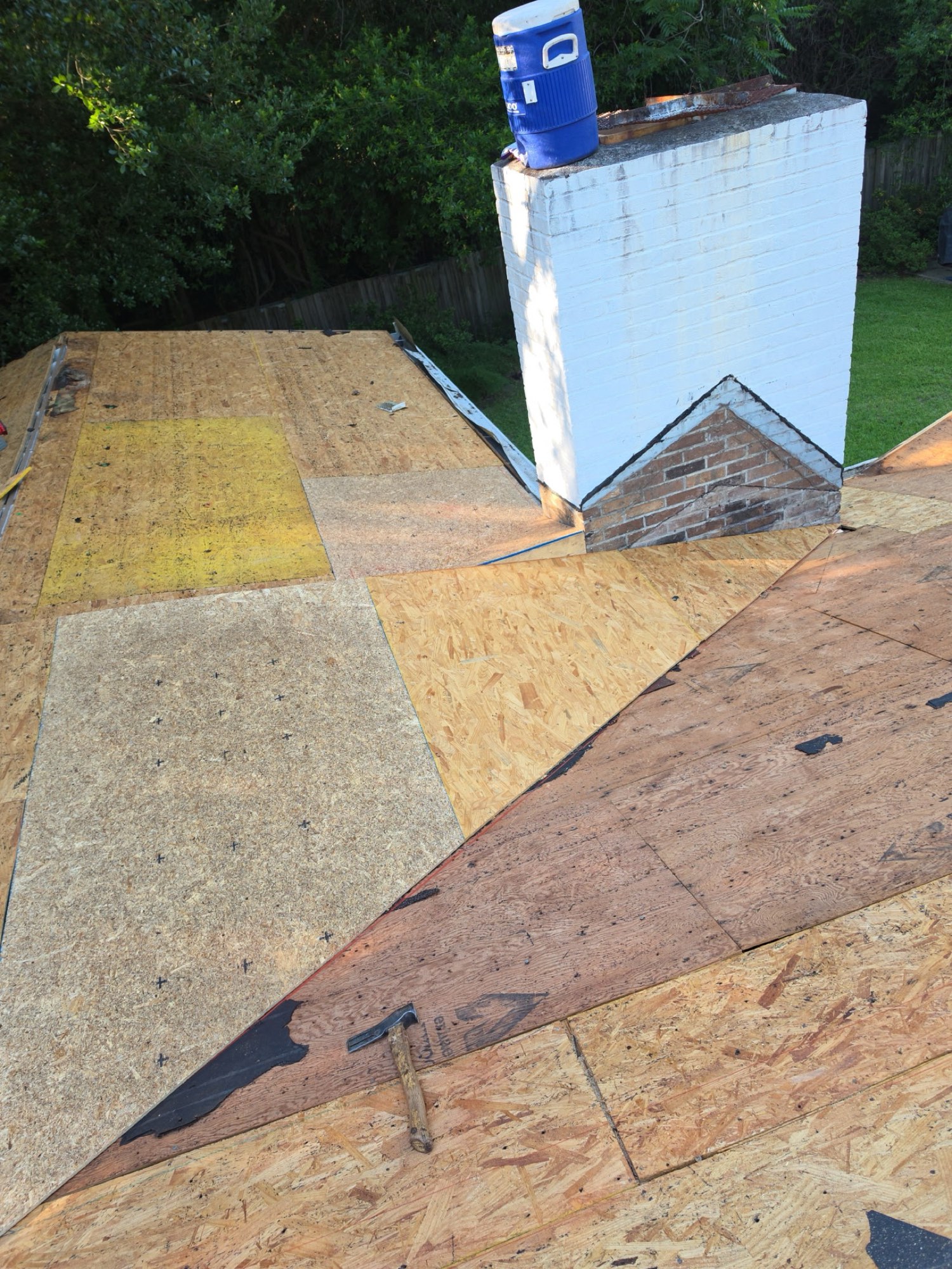 Rebuilt from the deck up: new plywood and OSB sheathing installed across the repaired slopes and tied in cleanly around the chimney