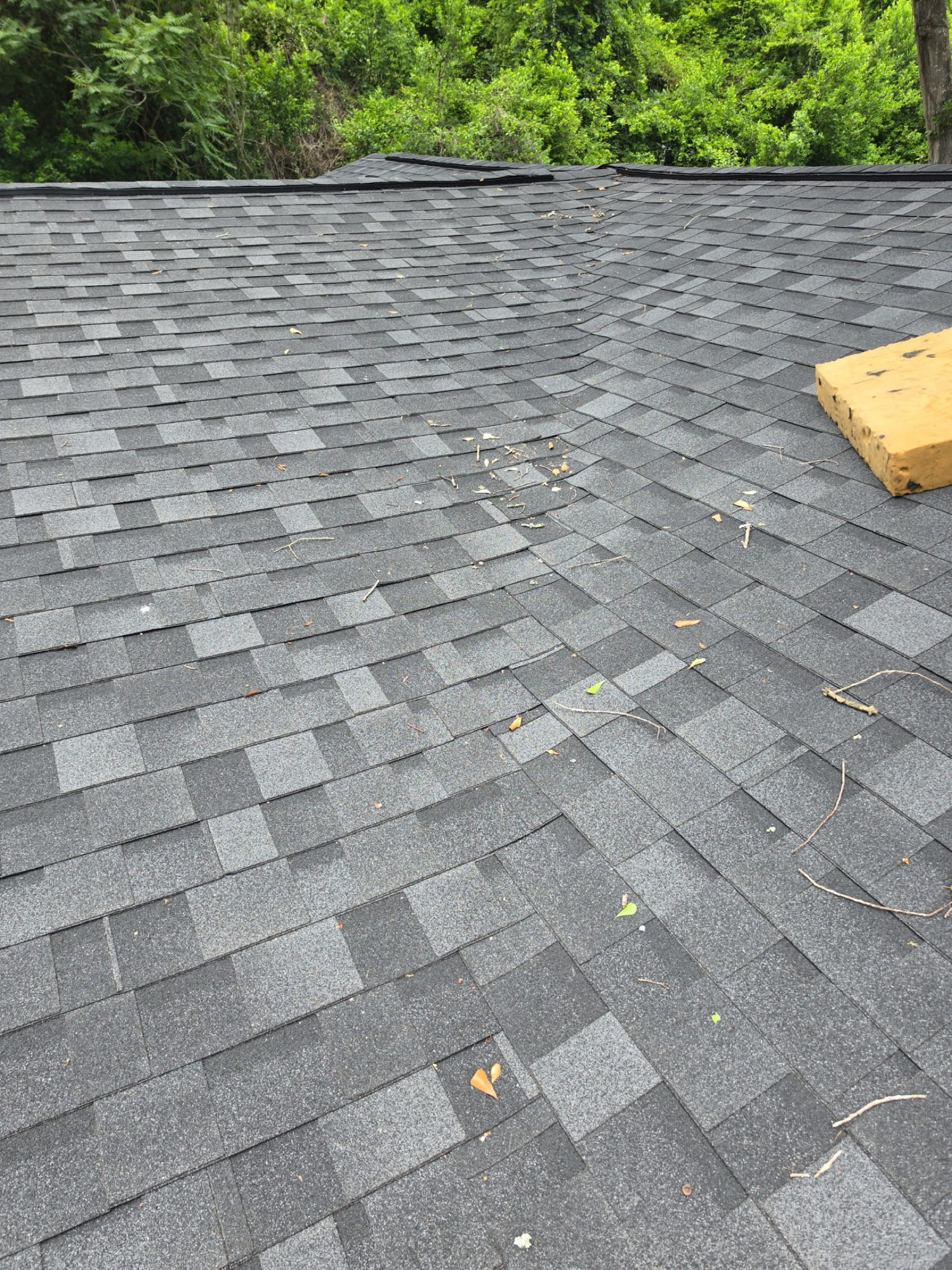 Finished: new architectural shingles laid tight and straight up to the ridge, with a properly finished hip line replacing the failing roof above