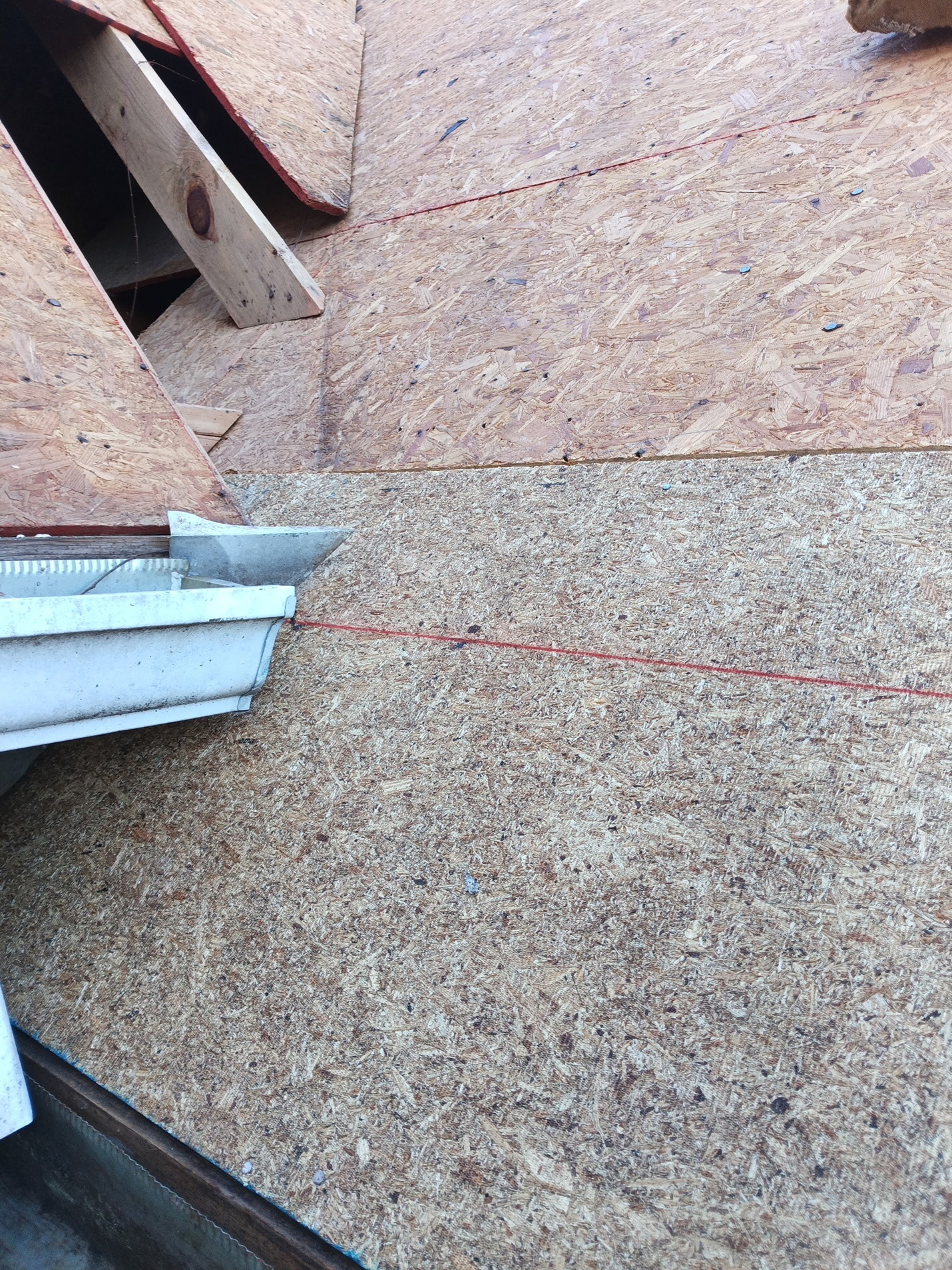Fresh plywood decking installed and snapped to chalk lines, with a new drip edge and gutter