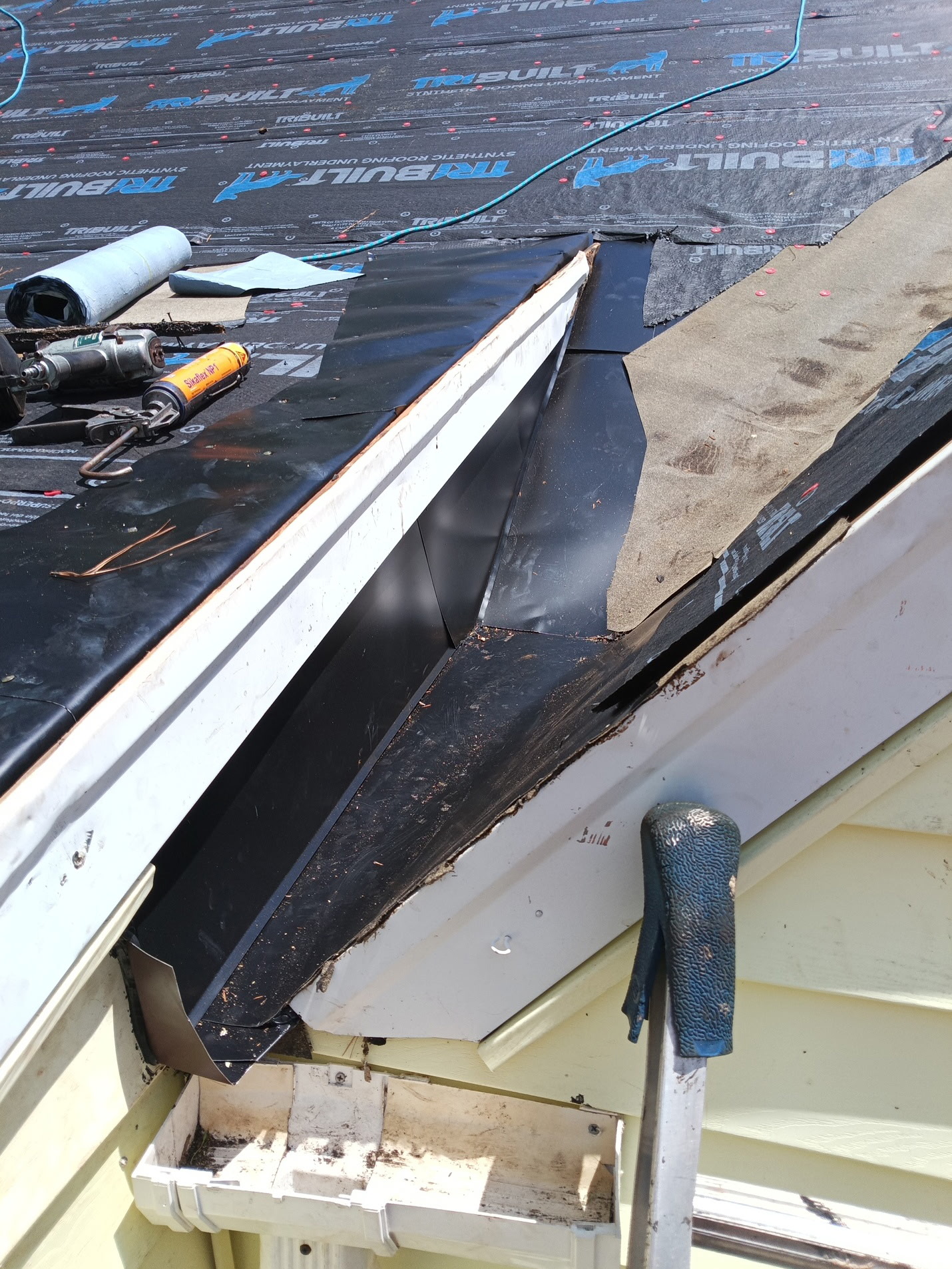 New synthetic underlayment, drip edge, and metal valley flashing set at the eave for leak protection