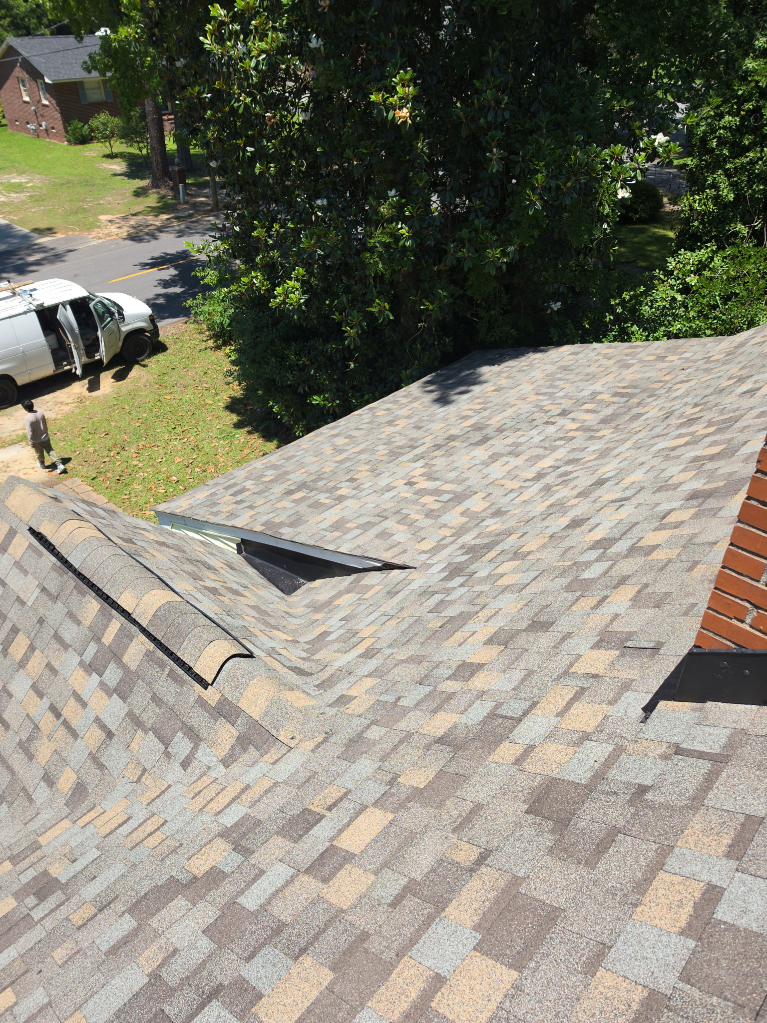 Finished: new architectural shingles across the complicated front slope, with the dormer and valleys tied in clean