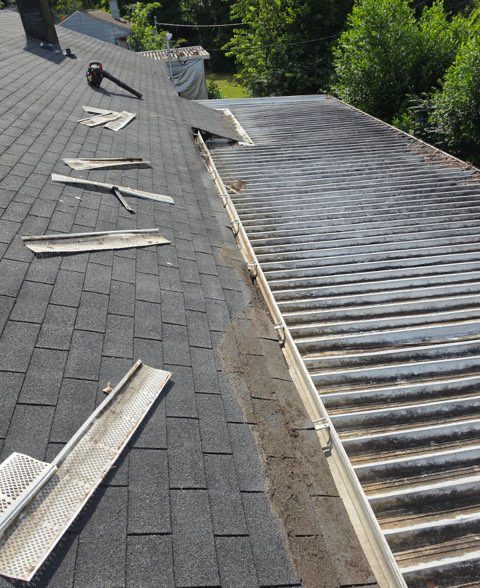 Repair underway: gutter guard sections lifted off and laid out on the roof so the run underneath