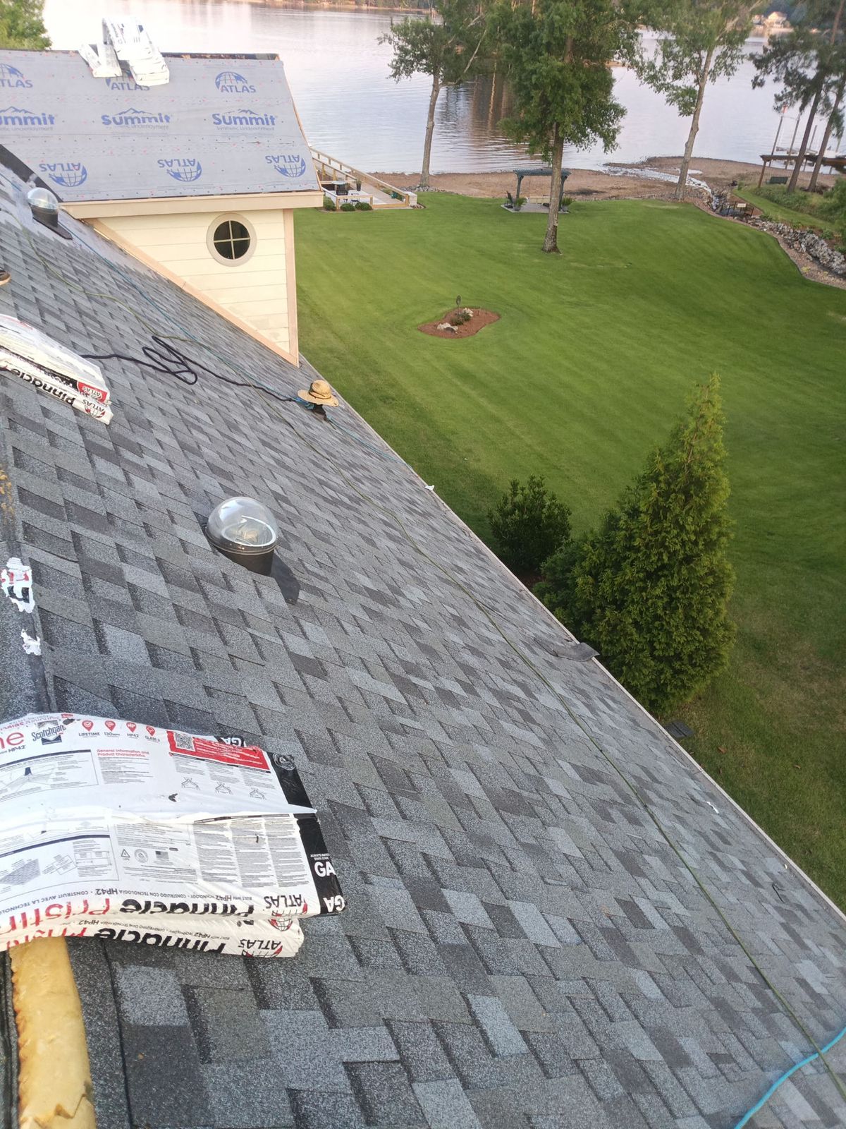 Installation underway: new shingles going down over synthetic underlayment, with fresh bundles