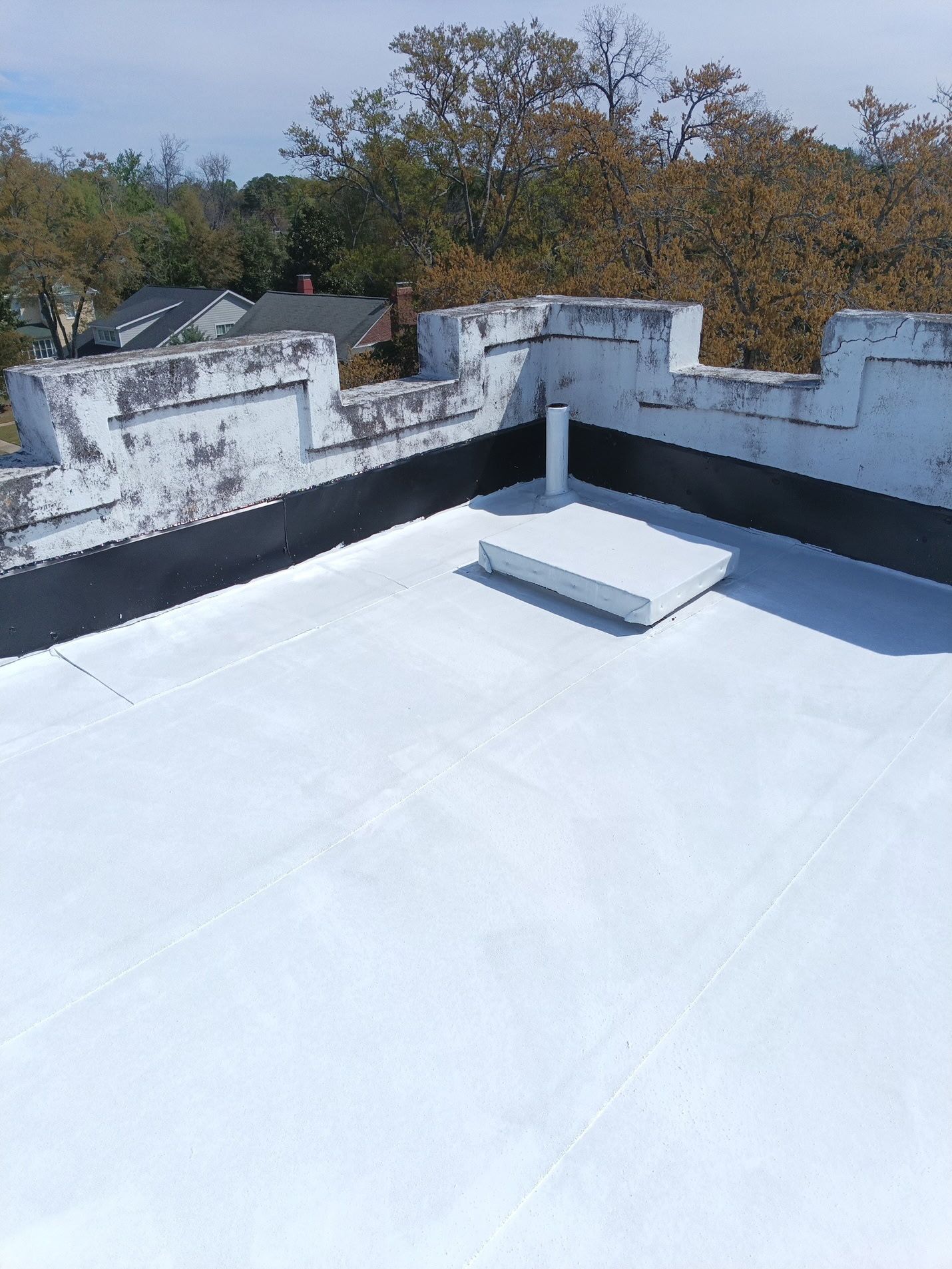 The tower's flat roof inside the stepped parapet, now a clean white surface with black flashing up