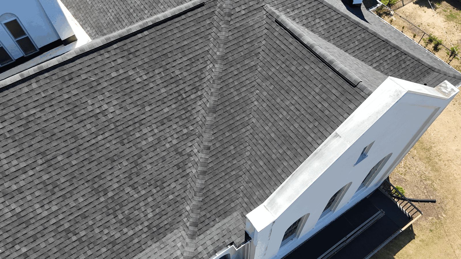 Finished: new charcoal architectural shingles across the main roof, with capped hips and vented
