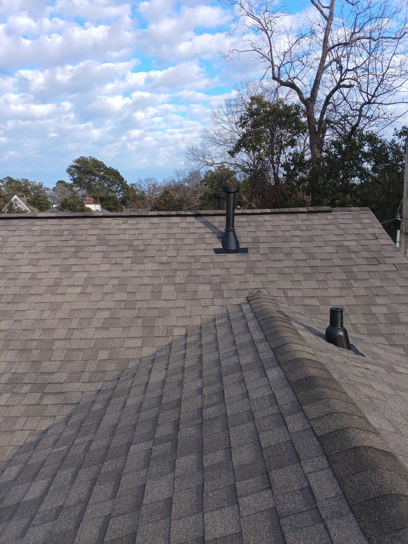 Finished: the new weathered-wood shingles with the hips and ridge capped, and new black pipe boots