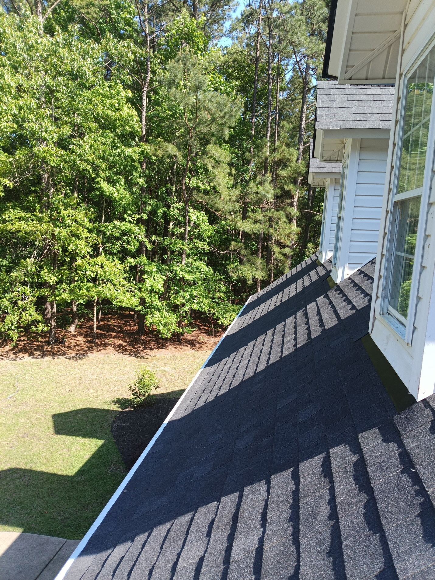 Finished: the lower porch roof carried up against the sided wall, its new shingles cut to a