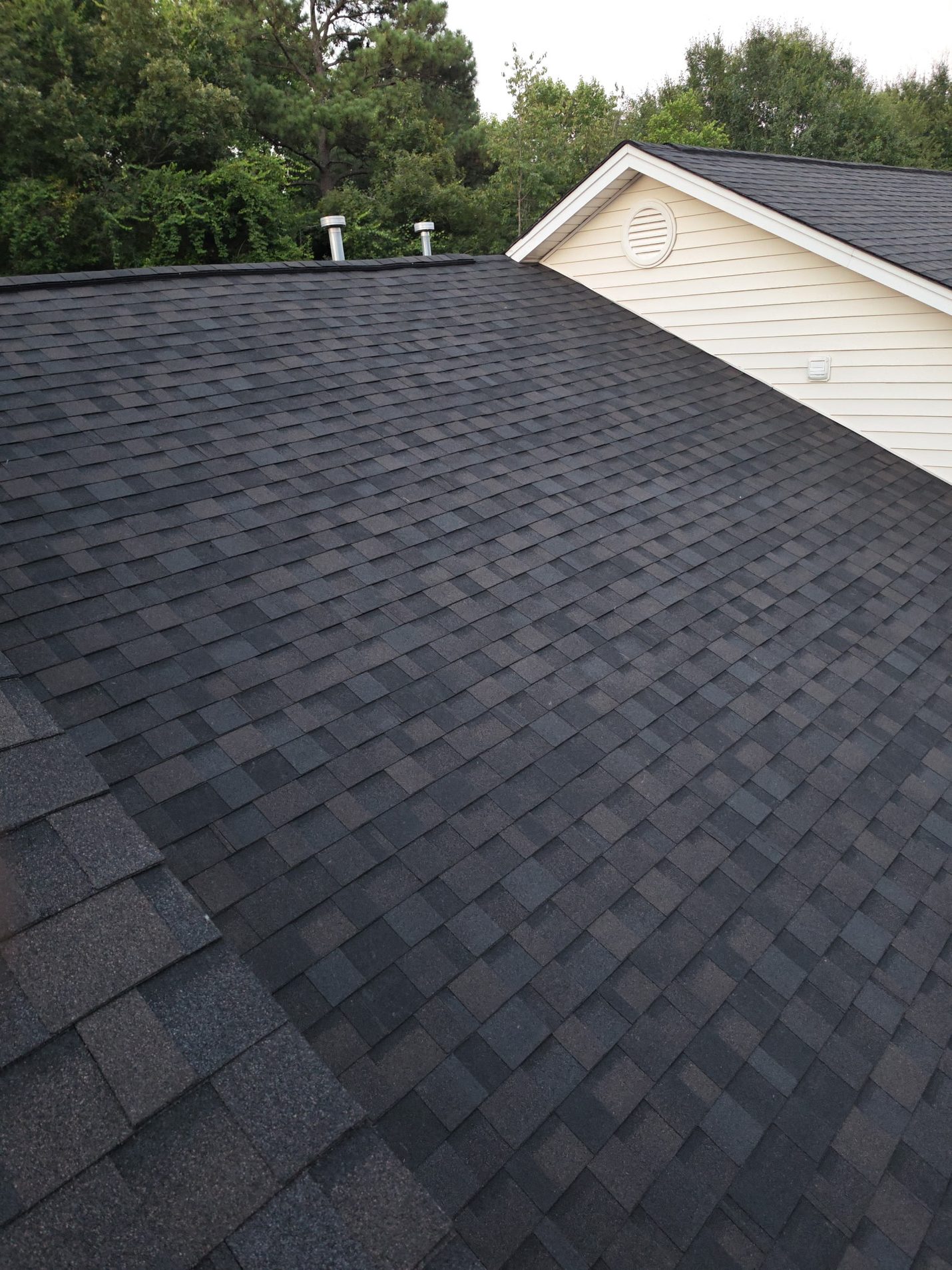Finished: the garage wing re-shingled to match, with new vent pipes set and flashed into the new