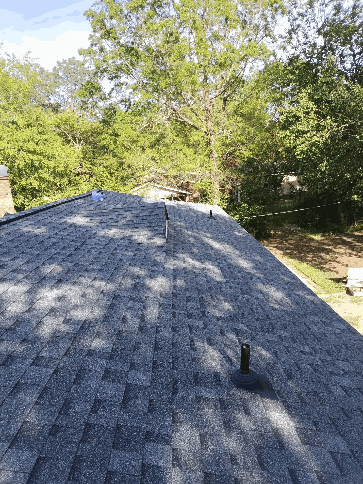 Finished: new charcoal architectural shingles across the rear slope, with a new boot on the