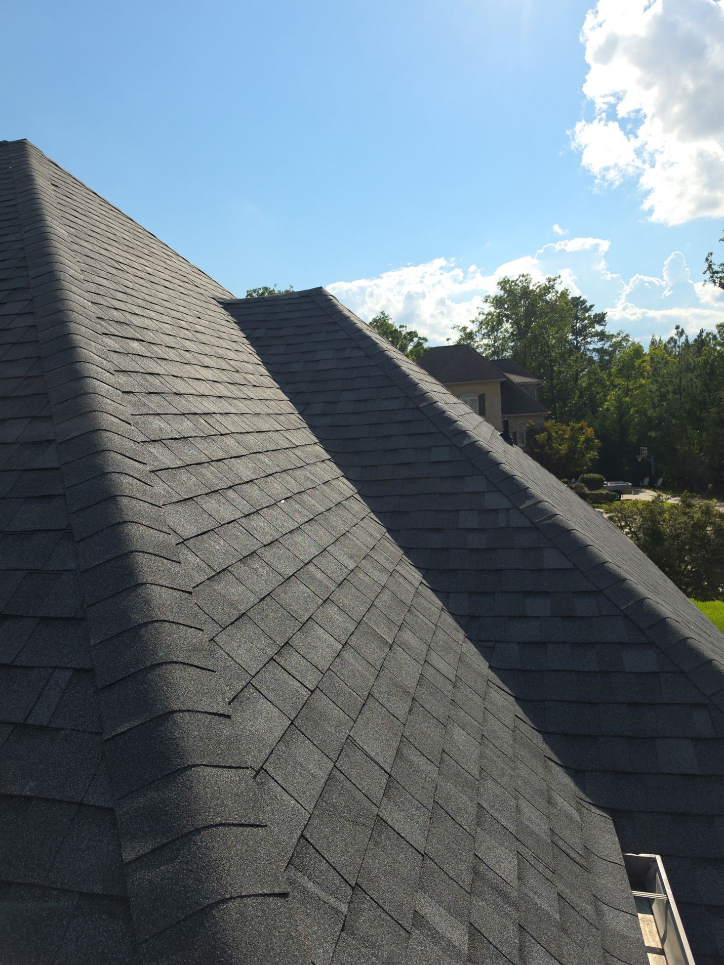 Finished: two hip slopes meeting in a clean valley, the new shingles running straight up to capped