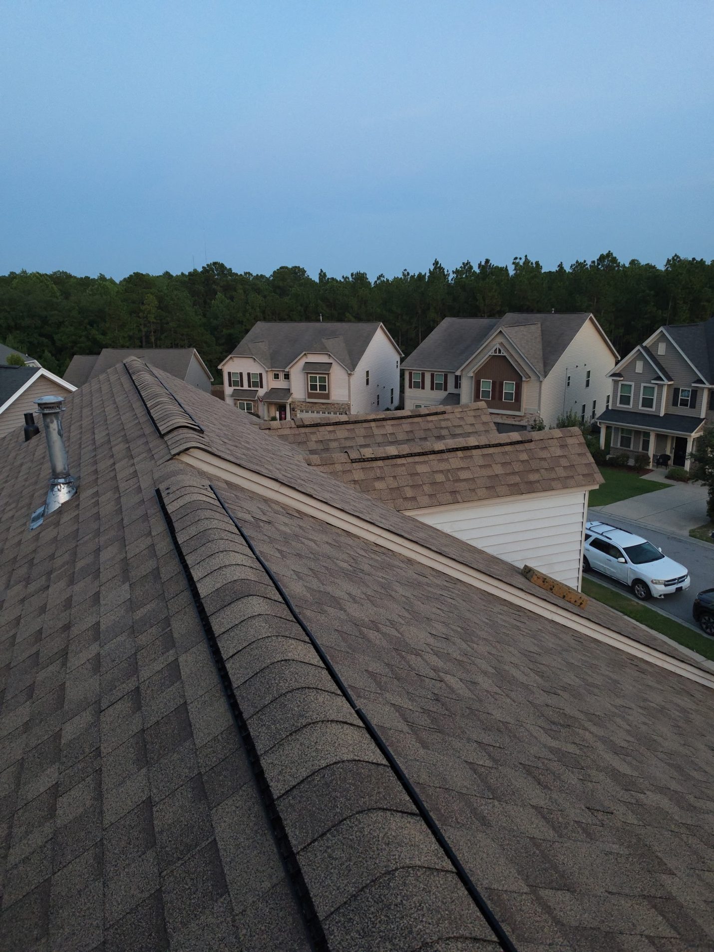 Finished: new ridge vent capped along the main ridge and the dormers beyond, in place of the