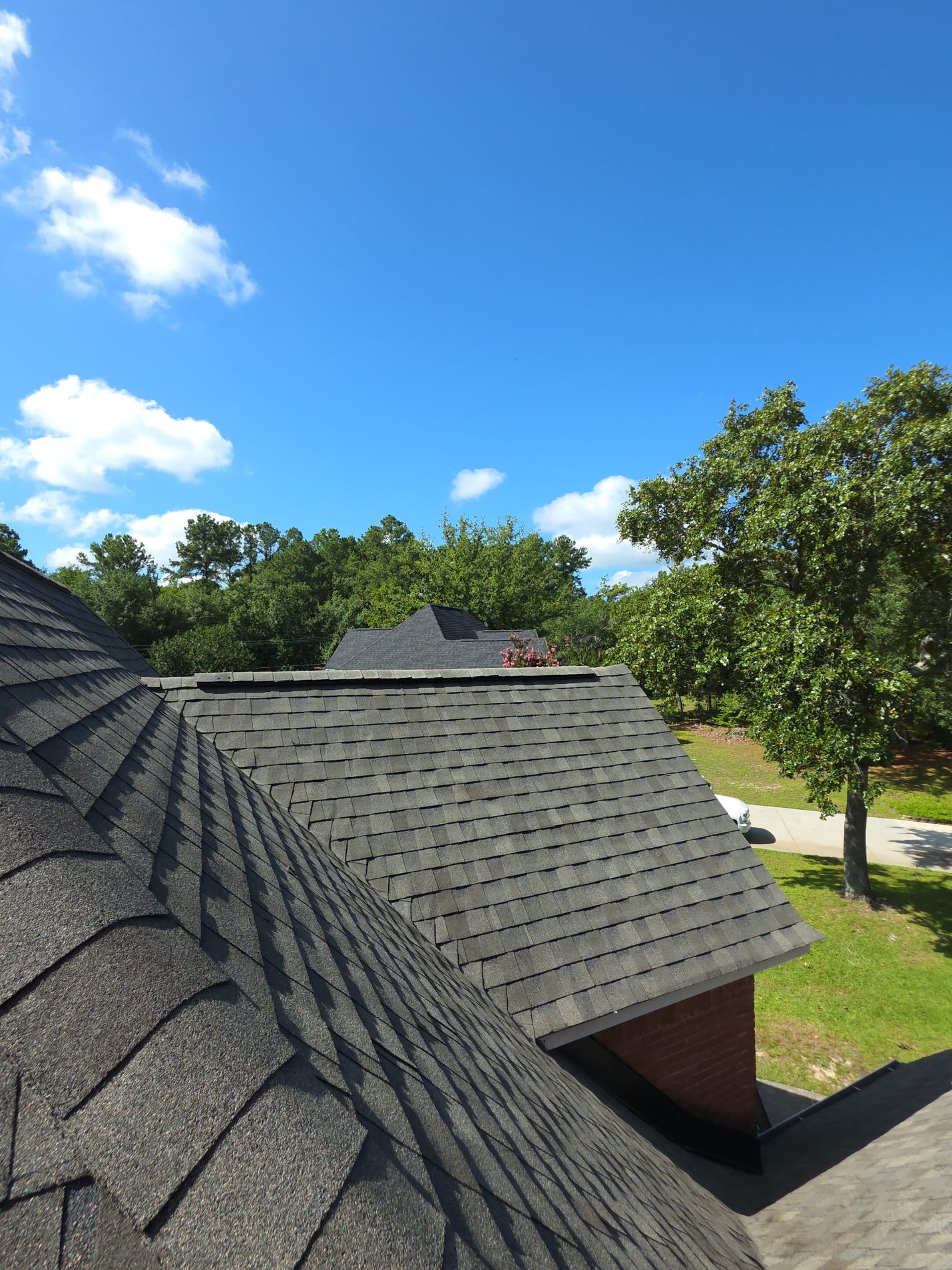 Finished: the side slopes in new architectural shingles, with the ridge capped and the hip tied in