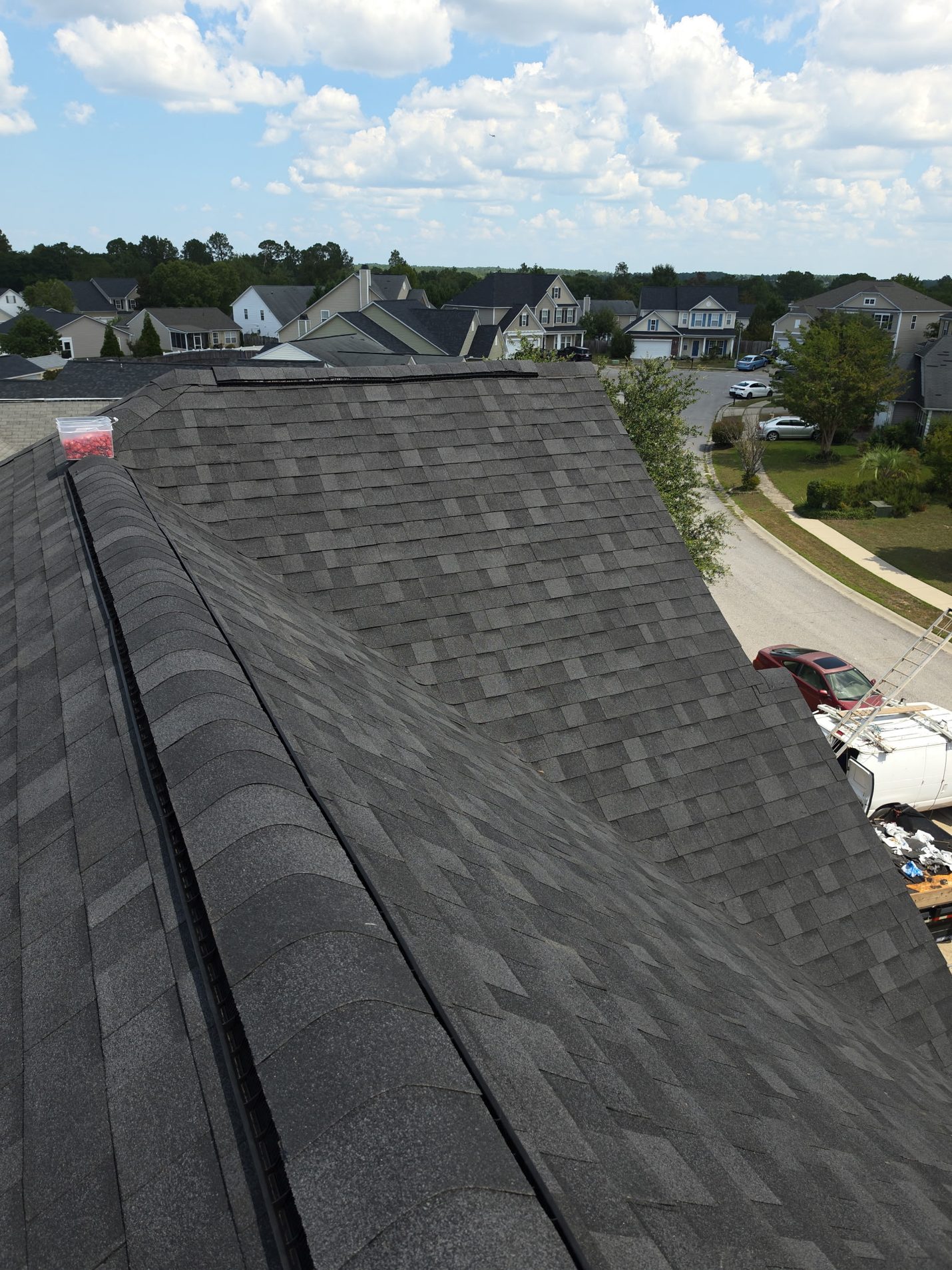 Finished: the front slopes and hip in new charcoal architectural shingles, capped along the ridge