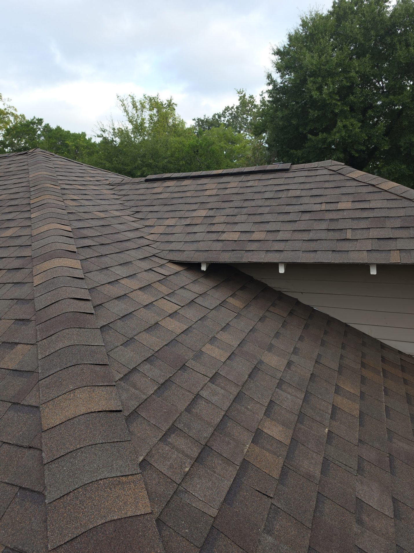 Finished: the low upper section and the hip below it in new shingles, with a low-profile vent